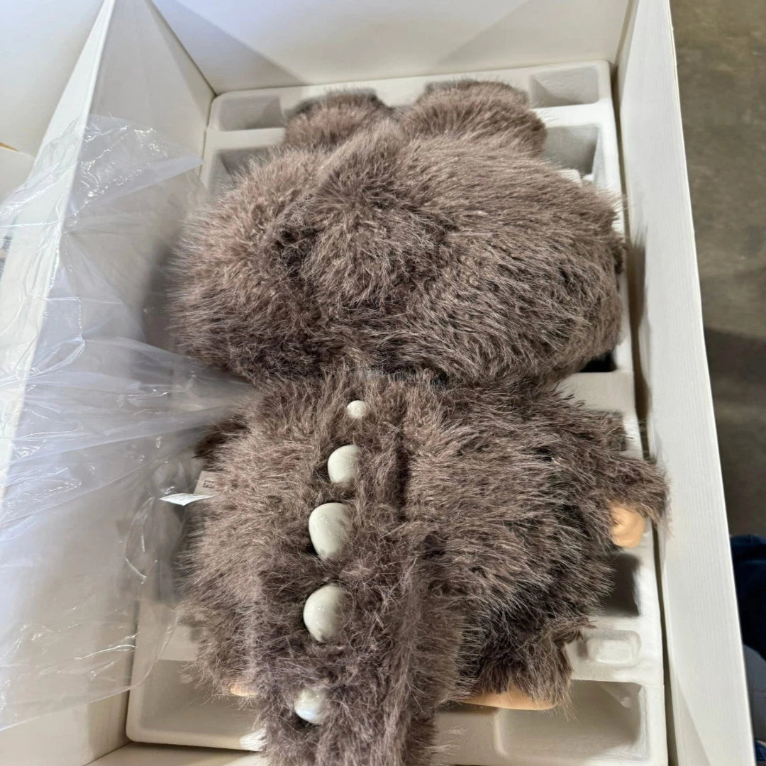 Plush toy resembling a character with a textured brown surface in a box.